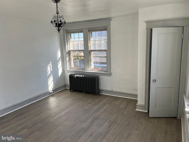 interior space featuring dark hardwood / wood-style flooring, radiator heating unit, and a chandelier