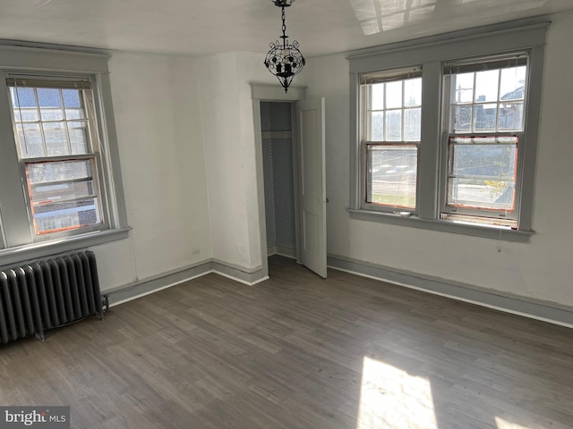 unfurnished bedroom with dark hardwood / wood-style flooring and radiator