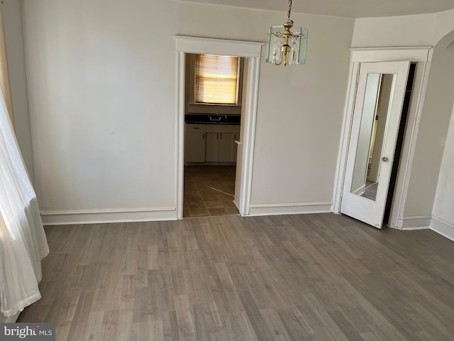 empty room featuring dark hardwood / wood-style flooring, sink, and an inviting chandelier