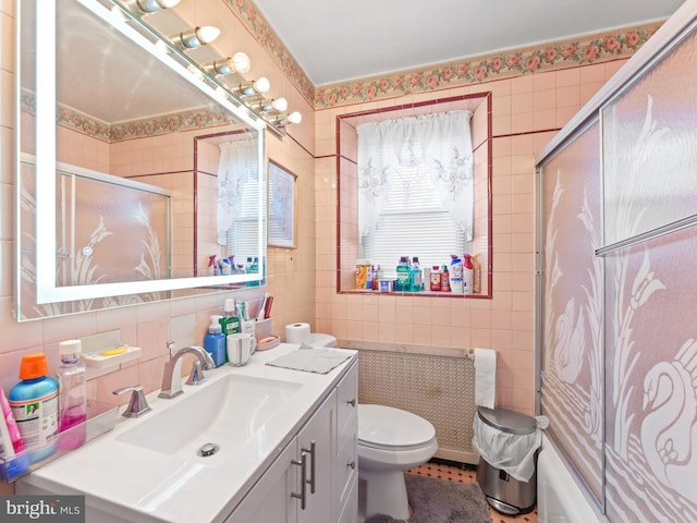 full bathroom with shower / bath combination with glass door, vanity, tile walls, and toilet