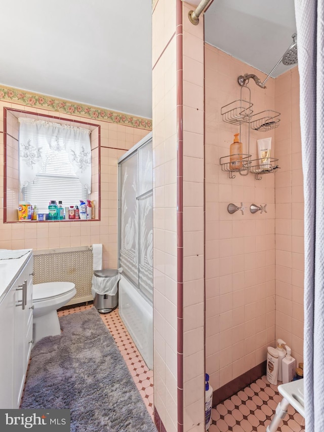 bathroom with a shower, tile patterned floors, tile walls, and toilet