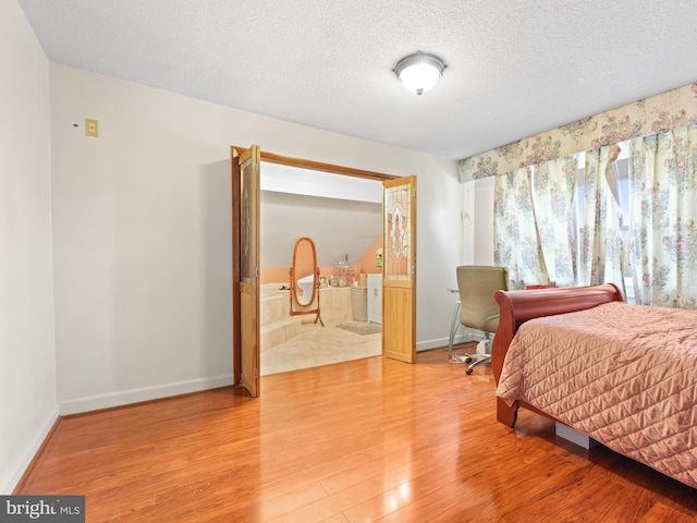 bedroom with ensuite bath, wood-type flooring, and a textured ceiling