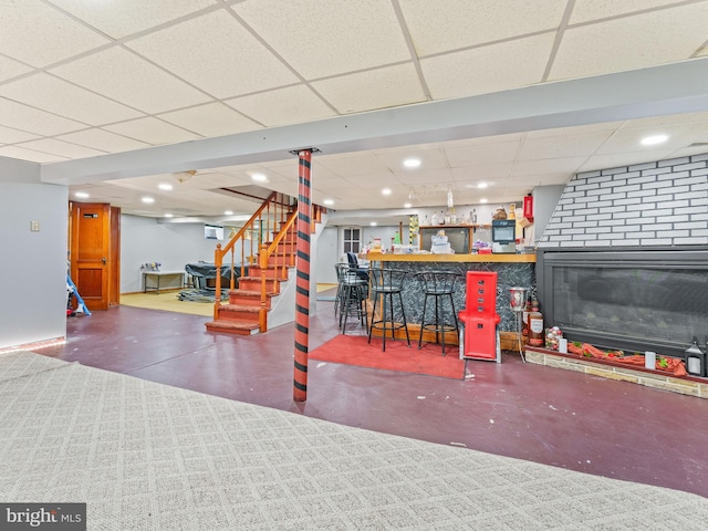 basement with a paneled ceiling, a fireplace, and bar