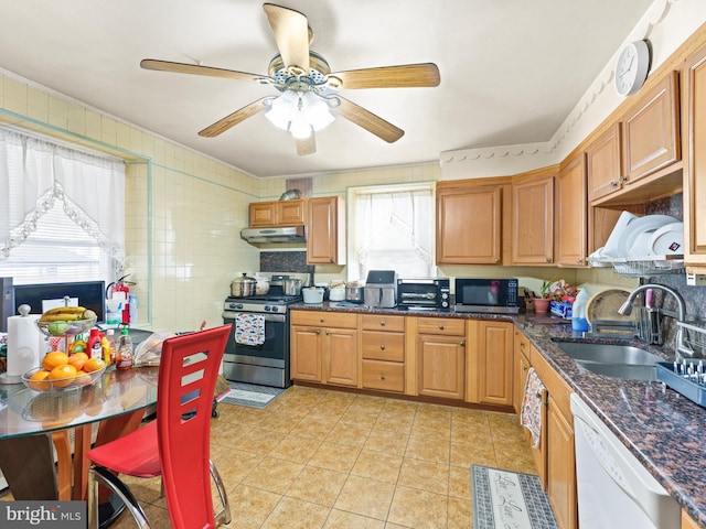 kitchen with stainless steel appliances, ceiling fan, sink, dark stone countertops, and light tile patterned flooring