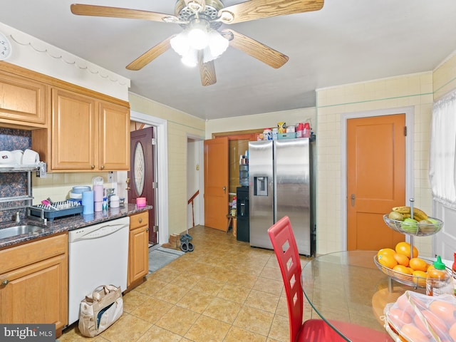 kitchen featuring stainless steel fridge, ceiling fan, sink, dark stone countertops, and dishwasher