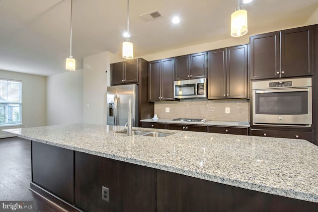 kitchen with dark brown cabinetry, stainless steel appliances, sink, and hanging light fixtures