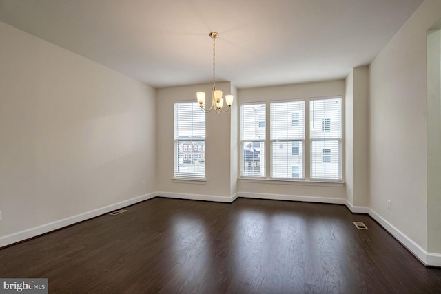 empty room with an inviting chandelier and dark hardwood / wood-style flooring