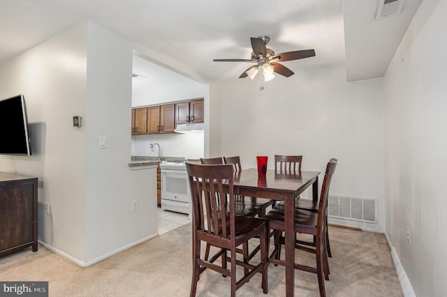 dining room featuring light carpet, sink, and ceiling fan