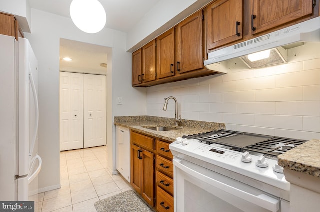 kitchen featuring backsplash, light tile patterned flooring, white appliances, and sink