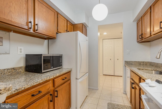 kitchen featuring light stone counters, sink, light tile patterned floors, and hanging light fixtures