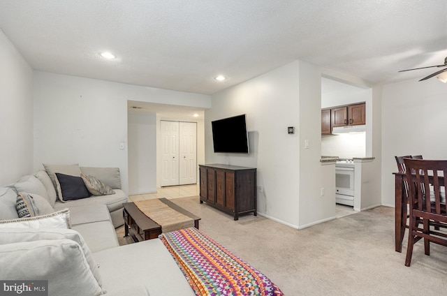 living room featuring light carpet, a textured ceiling, and ceiling fan