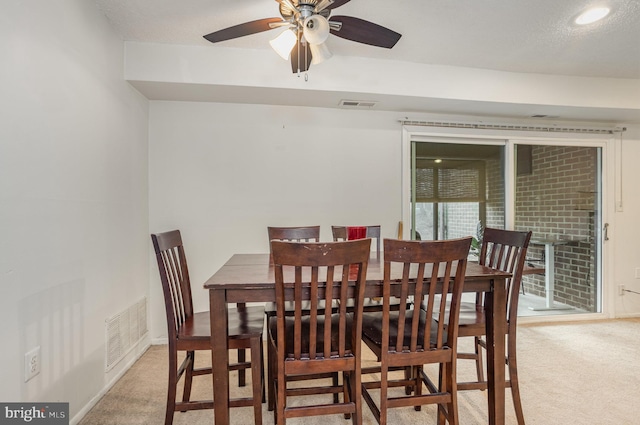 dining room with ceiling fan and light colored carpet