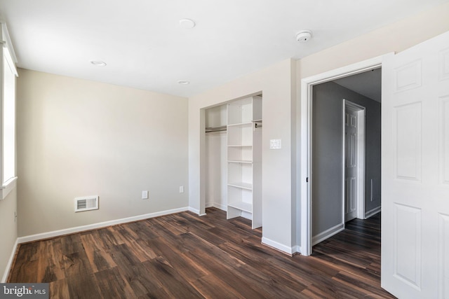 unfurnished bedroom featuring dark hardwood / wood-style flooring and a closet