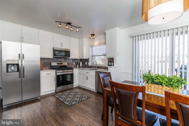 kitchen with stainless steel appliances, sink, dark hardwood / wood-style floors, white cabinets, and tasteful backsplash