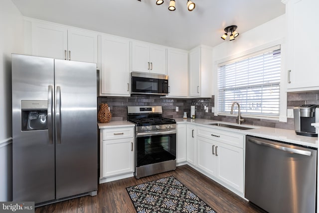 kitchen with backsplash, dark hardwood / wood-style flooring, white cabinets, appliances with stainless steel finishes, and sink