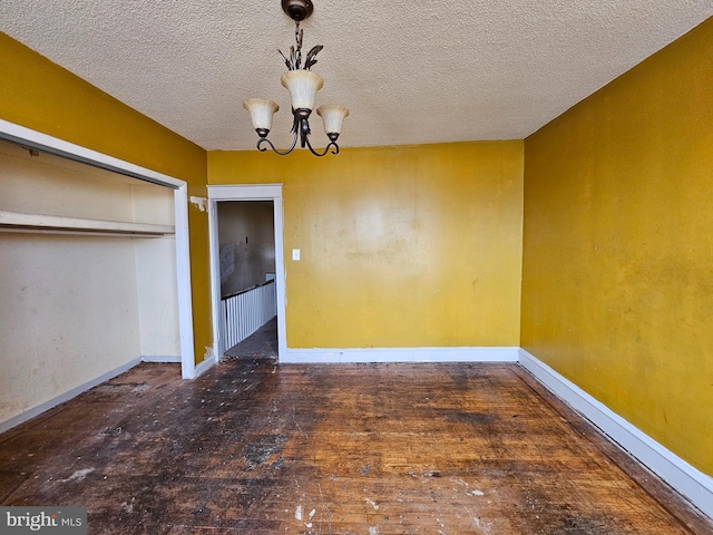 unfurnished dining area with a textured ceiling, an inviting chandelier, and dark wood-type flooring