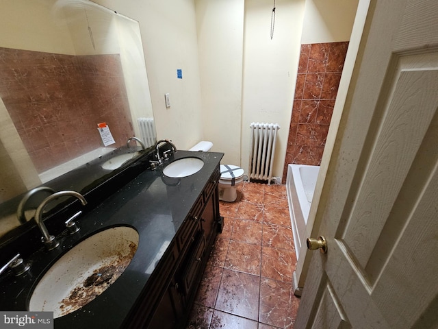 bathroom with radiator heating unit, vanity, a tub to relax in, and toilet