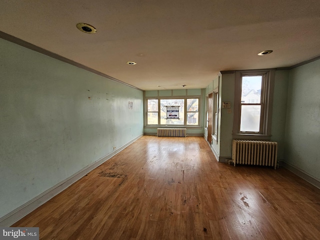 spare room with radiator heating unit, wood-type flooring, and ornamental molding