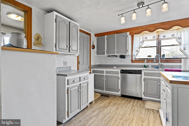 kitchen featuring gray cabinetry, dishwasher, light wood-type flooring, and sink