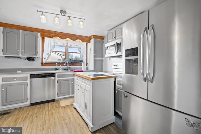 kitchen with appliances with stainless steel finishes, light wood-type flooring, gray cabinetry, and sink