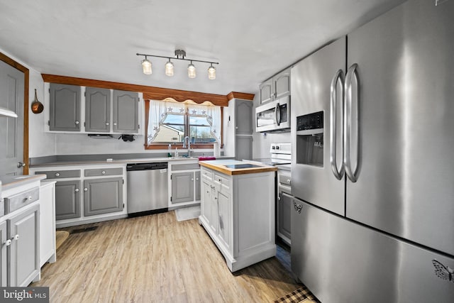 kitchen with wooden counters, light hardwood / wood-style floors, stainless steel appliances, sink, and gray cabinets