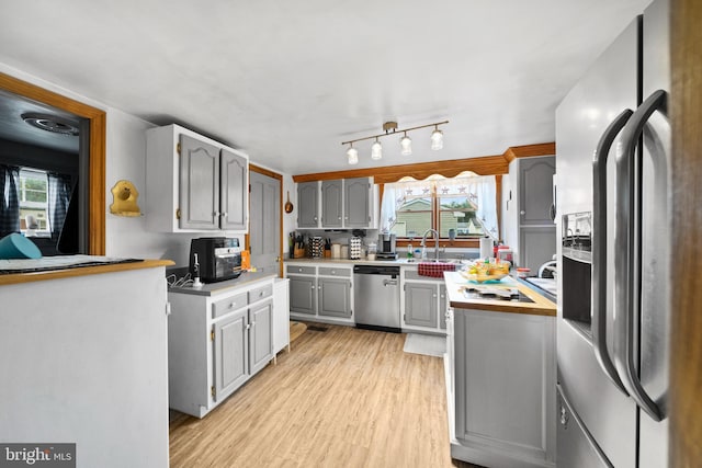 kitchen with sink, stainless steel appliances, gray cabinets, and light hardwood / wood-style flooring