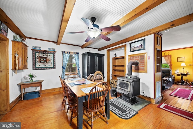 dining room featuring a wood stove, ceiling fan, light hardwood / wood-style floors, and ornamental molding