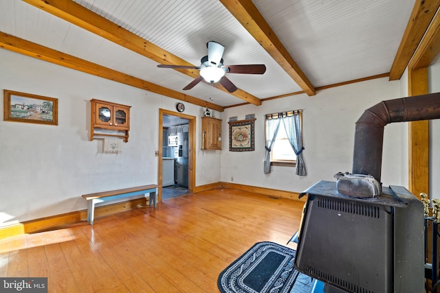 miscellaneous room featuring hardwood / wood-style floors, ceiling fan, and a wood stove