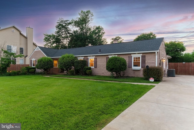 ranch-style house with a yard and central AC unit