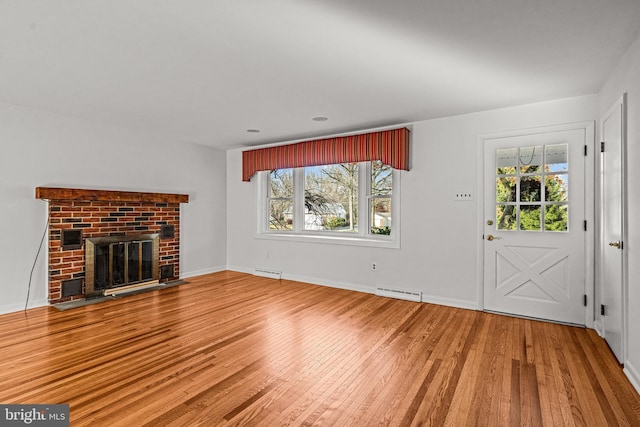 unfurnished living room featuring hardwood / wood-style floors and a brick fireplace