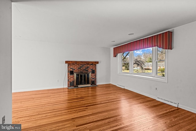 unfurnished living room featuring hardwood / wood-style floors and a brick fireplace