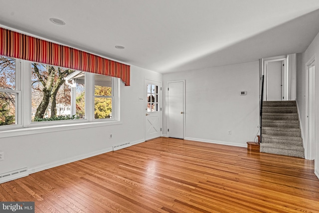 interior space with a baseboard heating unit and hardwood / wood-style flooring