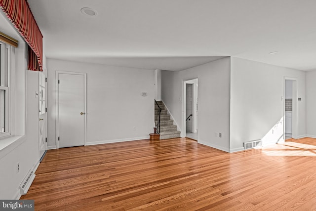 unfurnished room with light hardwood / wood-style flooring and a baseboard heating unit