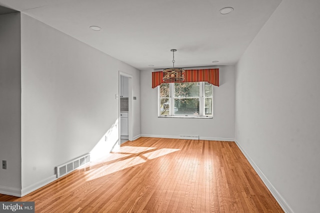 unfurnished dining area with hardwood / wood-style flooring and an inviting chandelier