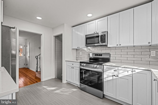 kitchen featuring decorative backsplash, white cabinets, and appliances with stainless steel finishes