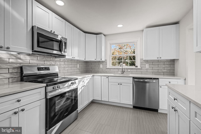 kitchen featuring decorative backsplash, sink, white cabinets, and stainless steel appliances