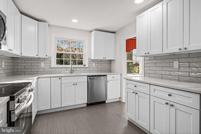 kitchen featuring light stone countertops, appliances with stainless steel finishes, backsplash, sink, and white cabinets