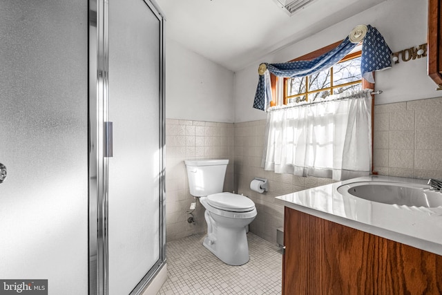 bathroom with walk in shower, tile patterned flooring, toilet, vanity, and tile walls