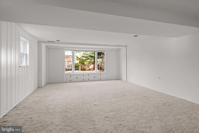 carpeted empty room featuring wood walls