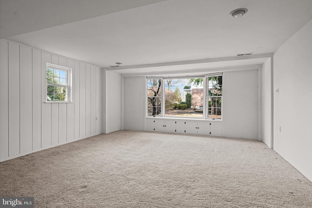 carpeted spare room featuring wooden walls