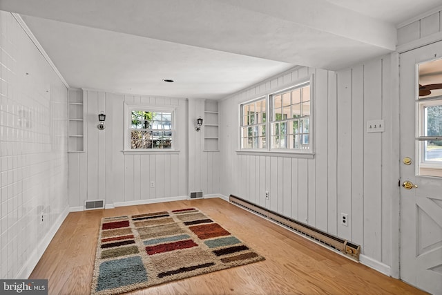 entrance foyer with hardwood / wood-style flooring, wooden walls, and a baseboard radiator