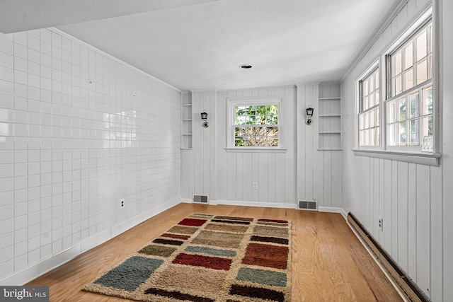 interior space featuring hardwood / wood-style floors, a baseboard radiator, and ornamental molding