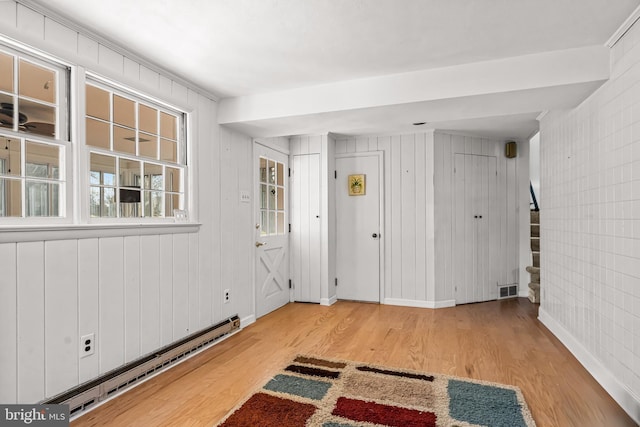 entryway featuring baseboard heating, wooden walls, and light hardwood / wood-style flooring