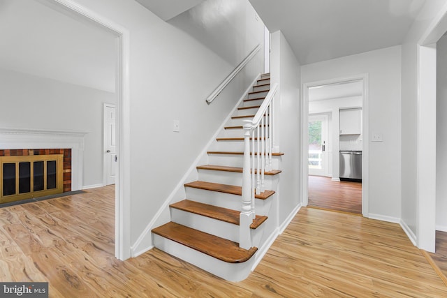 stairway with a fireplace and hardwood / wood-style floors