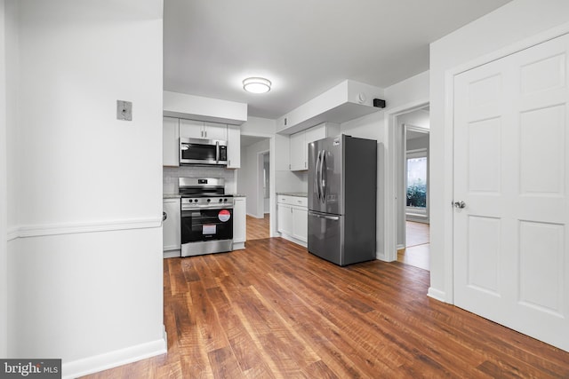 kitchen with tasteful backsplash, white cabinetry, dark hardwood / wood-style flooring, and stainless steel appliances