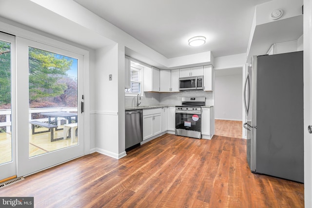 kitchen featuring decorative backsplash, dark hardwood / wood-style flooring, white cabinets, and appliances with stainless steel finishes