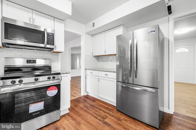 kitchen featuring white cabinets, decorative backsplash, stainless steel appliances, and light stone counters