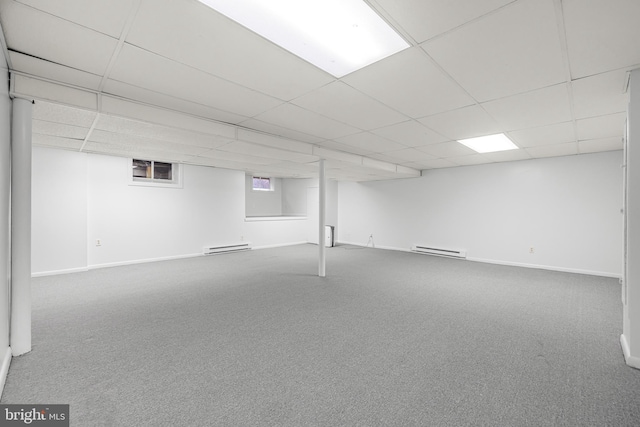 basement with carpet, a drop ceiling, and baseboard heating