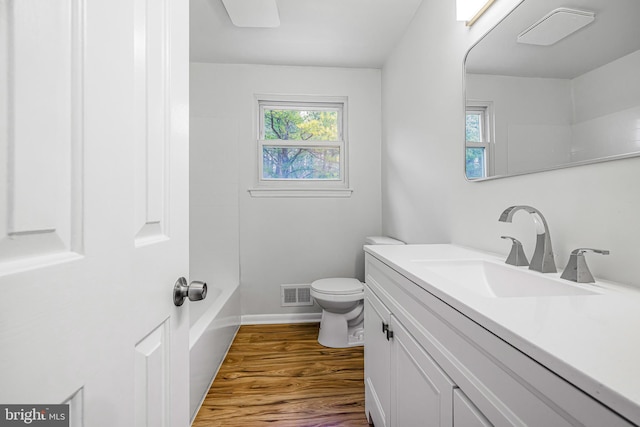 full bathroom with washtub / shower combination, wood-type flooring, vanity, and toilet