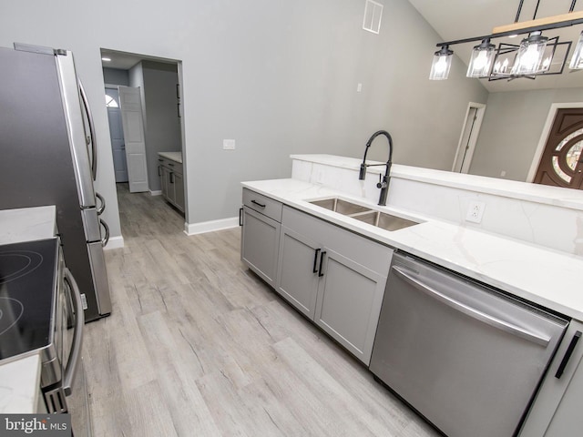 kitchen with stainless steel appliances, visible vents, light wood-style flooring, gray cabinetry, and a sink